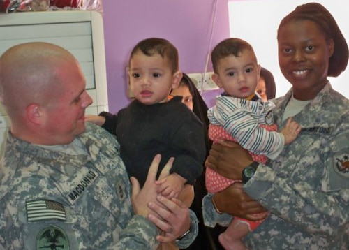 Navy Chief David McDonald, Master-at-arms, and Tech. Sgt. Sylvetris Rufus, 325th Fighter Wing Judge Advocate Paralegal and NCO in charge of general law, hold twins, Jesus and Moses, at the Rusafa Prison, Iraq. (U.S. Air Force courtesy photo)

