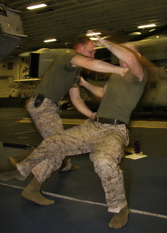 Sgt. Matthew Butler, motor transport chief, 24th Marine Expeditionary Unit, Marines executes a leg sweep on his Marine Corps Martial Arts Program instructor Cpl. Greg Chartrau, armory chief, 24th MEU during a MCMAP course inside the hangar bay aboard USS Nassau Feb. 23. The 24th MEU is currently deployed in the Central Command area of operations. The Marines continue to find any way possible to stay up to date in their training. (U.S. Marine Corps photo by Lance Cpl. David J. Beall)