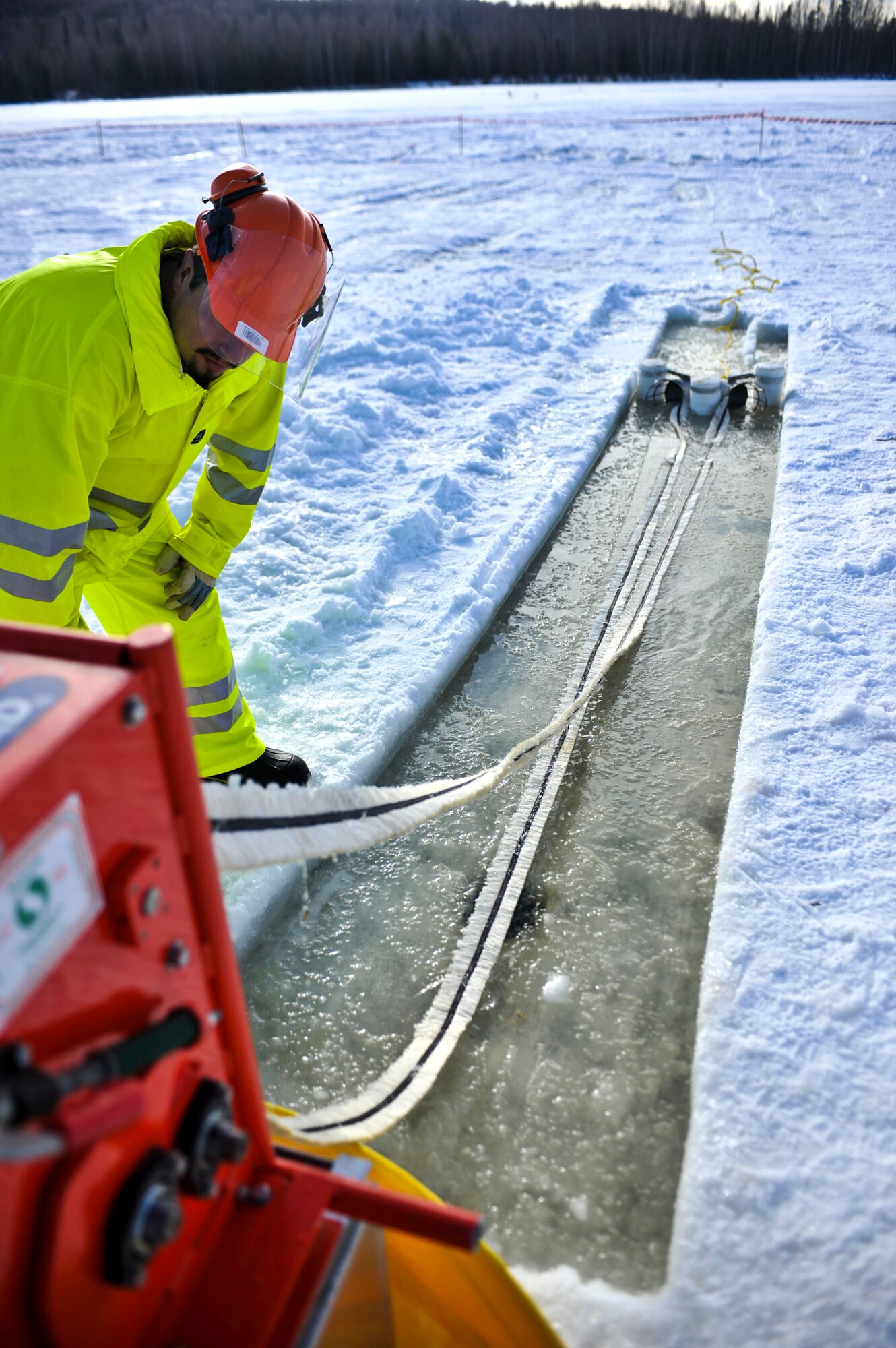 ELMENDORF AIR FORCE BASE, Alaska – A member from the 611th Civil Engineer Squadron ensures a rope-mop skimmer is working appropriately during Ice Ops 2010 Feb. 24 at Elmendorf’s Sixmile Lake. During this exercise members from the 611th CES, U.S. Coast Guardsmen and Navy's Supervisor of Salvage practiced with the equipment and techniques designed for surface and under-ice spills. Technicians use this training for real-world spill response, such as the recent fuel spills at Adak Island and the spill that resulted from tug that ran aground at Bligh Reef. (Air Force photo by Airman 1st Class Christopher Gross)