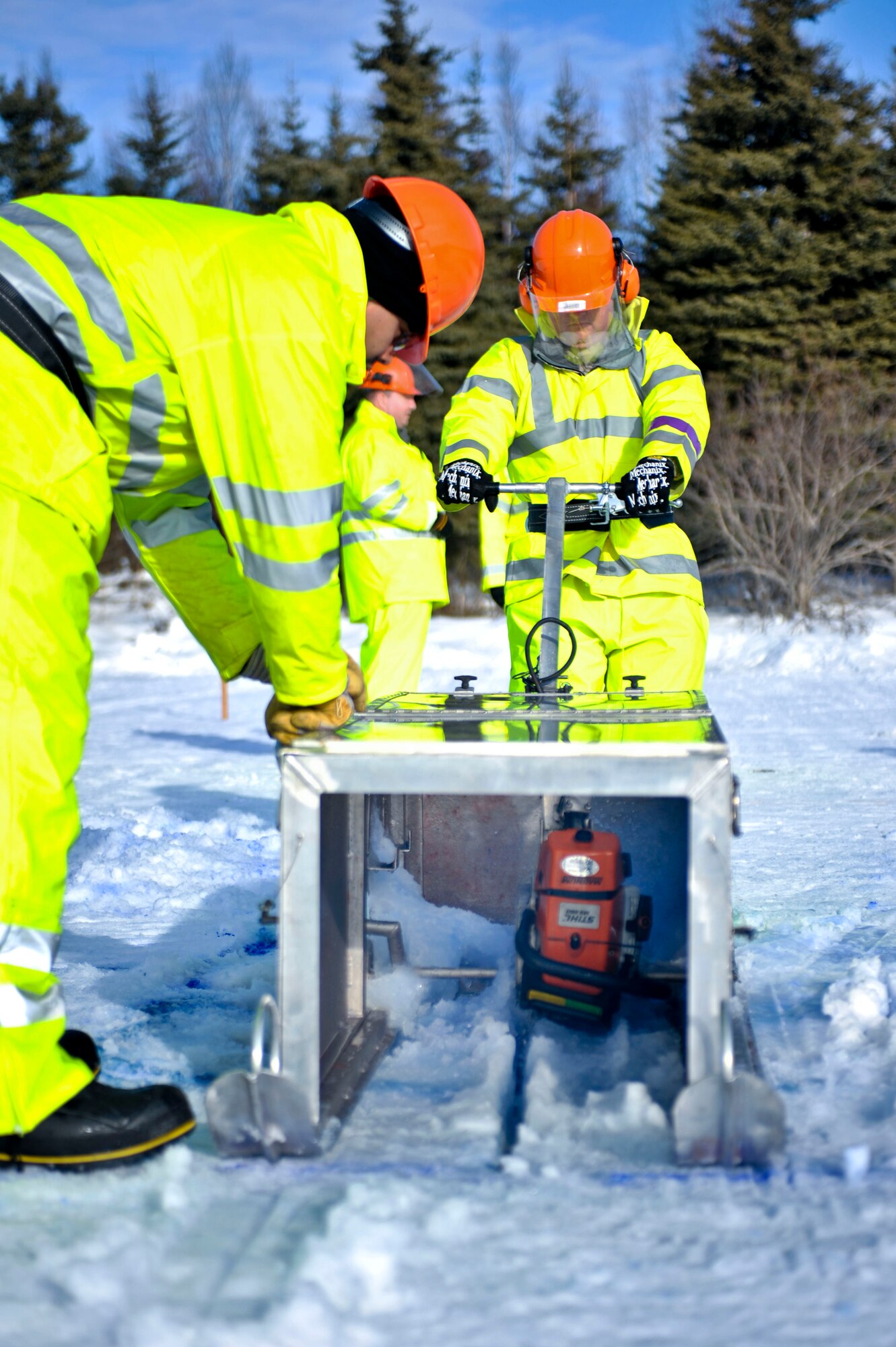 ELMENDORF AIR FORCE BASE, Alaska – Two members from the 611th Civil Engineer Squadron cut through the ice with an enclosed chain saw at Elmendorf’s Sixmile Lake during Ice Ops 2010 Feb. 24. During this exercise members from the 611th CES, U.S. Coast Guardsmen and Navy's Supervisor of Salvage practiced with the equipment and techniques designed for surface and under-ice spills. Technicians use this training for real-world spill response, such as the recent fuel spills at Adak Island and the spill that resulted from tug that ran aground at Bligh Reef. (Air Force photo by Airman 1st Class Christopher Gross)