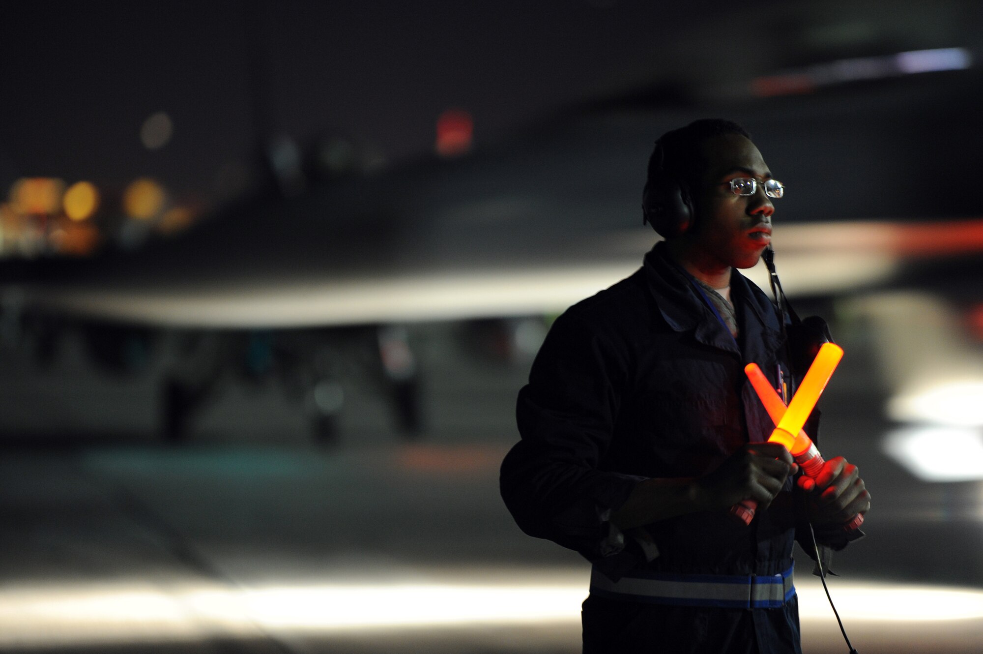 NELLIS AIR FORCE BASE, Nev. -- Airman 1st Class Eric Gordon 20th Aircraft Maintenance Squadron, crew chief from Shaw AFB, S.C. uses flashlights to hold an F-16 while another F-16 taxis toward down the flightline for a night training mission at Red Flag 10-3 Feb. 23, 2010.  Red Flag is a realistic combat training exercise involving the air forces of the United States and its allies. The exercise is conducted on the 15,000-square-mile Nevada Test and Training Range, north of Las Vegas. (U.S. Air Force photo by Tech. Sgt. Michael R. Holzworth/RELEASED)