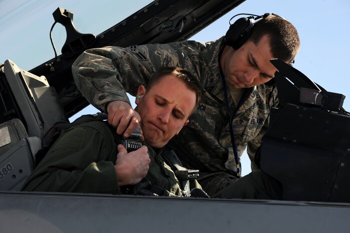 NELLIS AIR FORCE BASE, Nev. -- Airman 1st Class Joshua Koch 20th Aircraft Maintenance Squadron, crew chief from Shaw AFB, S.C. helps 1st Lt. Greg Farrell a 55th Fighter Squadron, pilot also from Shaw get strapped into his F-16 before a training mission at Red Flag 10-3 Feb. 23, 2010.  Red Flag is a realistic combat training exercise involving the air forces of the United States and its allies. The exercise is conducted on the 15,000-square-mile Nevada Test and Training Range, north of Las Vegas. (U.S. Air Force photo by Tech. Sgt. Michael R. Holzworth/RELEASED)