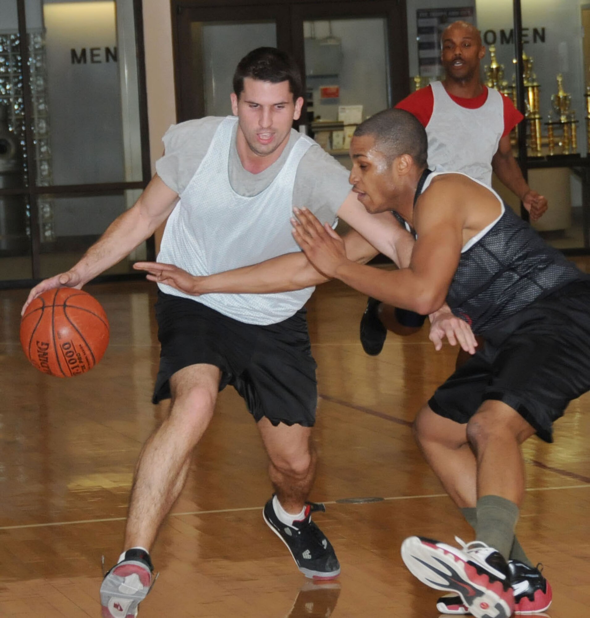 Ryan Rice, 81st FSS-CPTS, drives past Dorian Rodgers, 335th TRS, as Sean Morgan, 81st FSS-CPTS, the league’s most valuable player, looks on.  The 81st FSS-CPTS won the championship game, 49-42.   (U.S. Air Force photo by Kemberly Groue)
