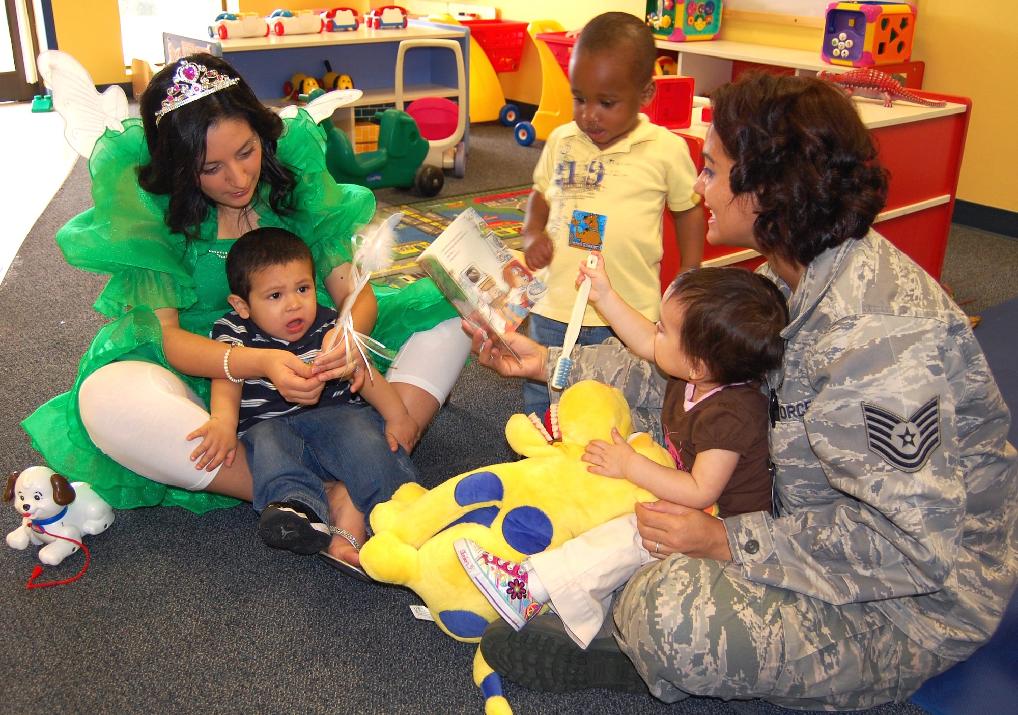 Tech. Sgt. Caroline Bunce, right, 81st Dental Squadron dental hygienist, holds Eva Munoz while “Tooth Fairy” Senior Airman Veronica Reesey, an 81st DS dental assistant, holds AJ Lujano, while Darius Johnson concentrates on the book Sergeant Bunce is reading to them Feb. 9 at the child development center. Squadron members visited the CDC as part of their Children’s Dental Health Month activities to read to the 1-year-old group and used stuffed animals during play to show the children how to brush their teeth.  Eva’s parents are Senior Airmen Laura Munoz, 81st Surgical Operations Squadron, and Jacob Munoz, 81st DS.  AJ’s parents are Senior Airman Mirna Lujano, 81st Logistics Readiness Squadron, and Angel Lujano.  Darrius’ mother is Airman 1st Class Deanna Johnson, 81st Communications Squadron. The squadron conducted a puppet show Feb. 10 at the CDC for older children.  (U.S. Air Force photo by Steve Pivnick)