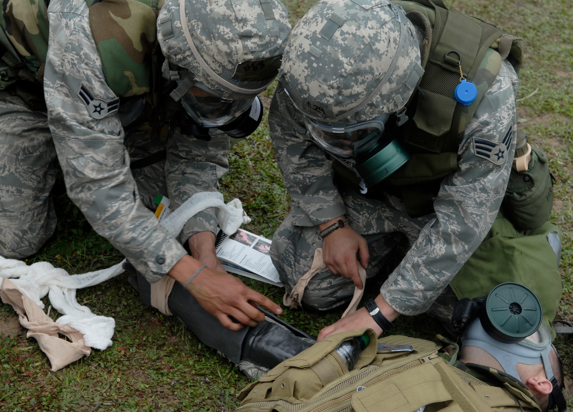 VANDENBERG AIR FORCE BASE, Calif. -- Using an Airman's Manual for reference, Airman 1st Class Zachariah Stone and Senior Airman Scott Gallegos perform self-aid and buddy care on Senior Airman Thomas Newman at the North Star exercise site here Thursday, Feb. 18, 2010. Each Airman at North Star is trained and evaluated on SABC procedures to prepare them for real world situations. (U.S. Air Force photo / Senior Airman Ashley Reed)