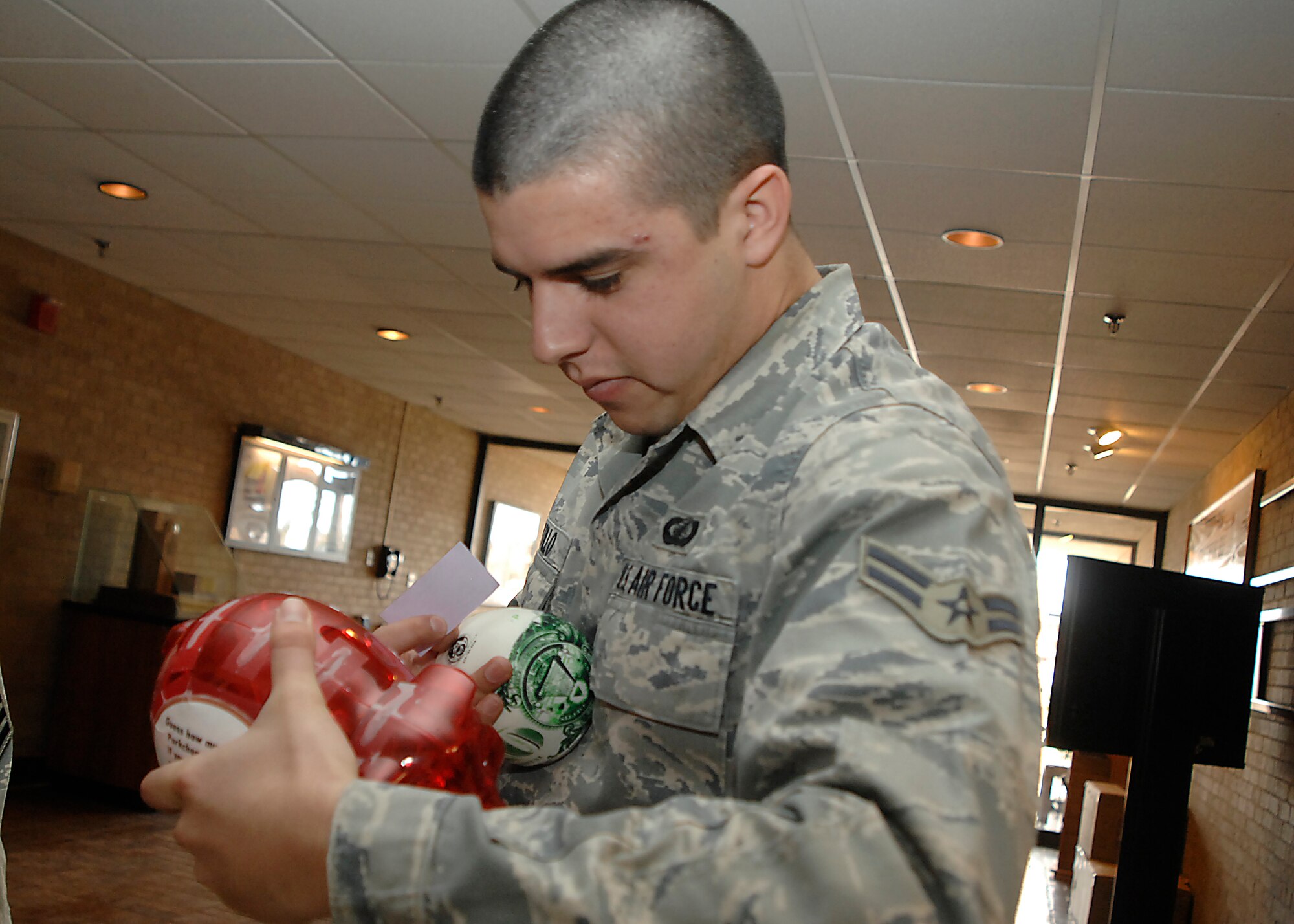 Airman 1st Class Brian Castillo, 27th Special Operations Comptroller Squadron, tries to guess how much money is in the piggy bank Feb. 24 at Cannon Air Force Base, N.M. The best guesser won the money. Feb. 21-28 is America Saves Week and Airman and Family Readiness Center workers Tom Hittle and Linda Sapp handed out free piggy banks, stress balls and key chains to remind Airmen to think about their savings plans. (U.S. Air Force photo by Greg Allen)