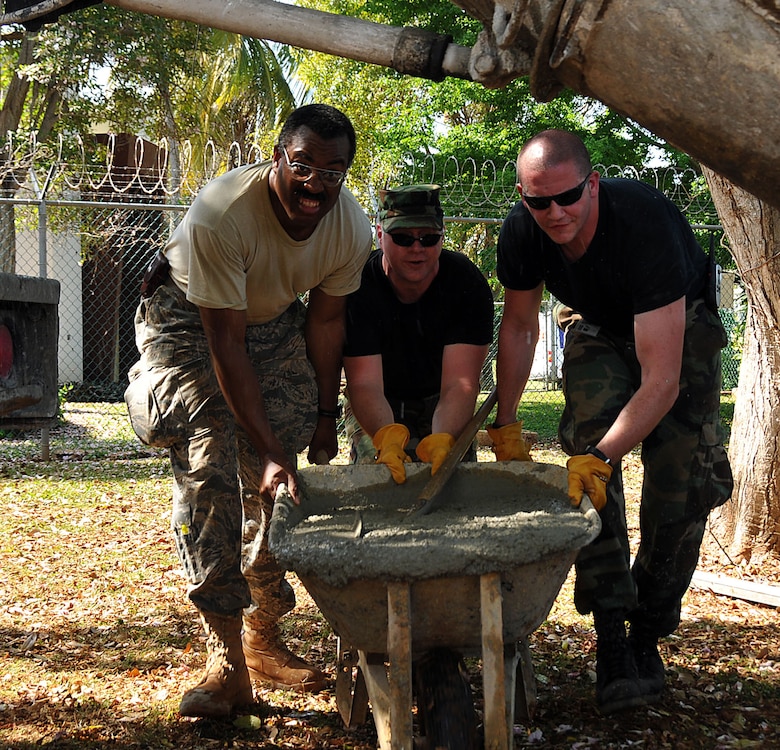 COAST GUARD AIR STATION BORINQUEN, Puerto Rico --  Three members of the 176th Civil Engineer Squadron push a wheelbarrow full of wet concrete to a job site here Feb. 11, 2010. They are (left to right) Master Sgt. Brian Lewis; Tech. Sgt. David Bailey, and Staff Sgt. Cody Grella. The three are among 45 squadron members who spent two weeks here in early February to train and sharpen their skills on a wide range of infrastructure projects, upgrades and renovations. The squadron undertakes such a mission --  called a Deployment for Training, or DFT -- every year or two. Recent DFTs have taken the squadron's men and women to Israel, Southern California, Hawaii, Ecuador, Okinawa, Minnesota and Texas. AKANG photo by 1st. Lt. John Callahan. 