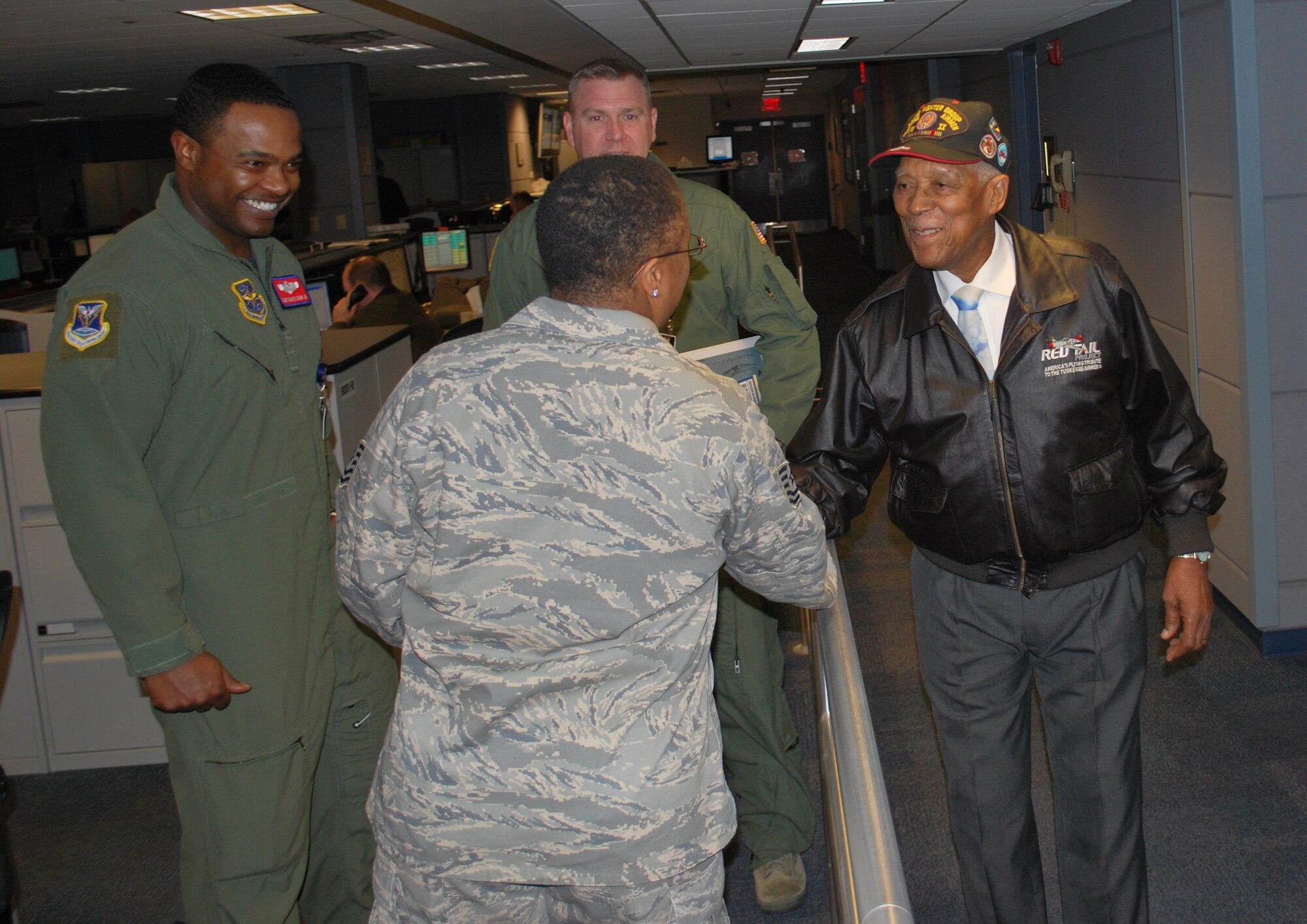 Retired Tech. Sgt. George Watkins, Sr. (far right), a member of the Tuskegee Airmen, shakes hands with Tech. Sgt. Tonia Elliott, 618th Tanker Airlift Control Center Current Operations Directorate, on the 618th TACC's operations floor Feb. 23.  Mr. Watkins, who served in the military for 26 years as an aircraft and missile electrician, toured the 618th TACC to learn about current-day operations and met with Airmen to share his experiences in Air Force history.  (U.S. Air Force photo/Capt. Justin Brockhoff)