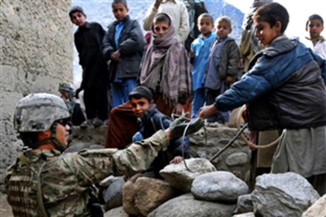 U.S. Army Staff Sgt. Dennis L. Famisan borrows a toy from a young boy in the village of Kandagal in the Monagai district of eastern Afghanistan’s Kunar province, Feb. 20, 2010. The unit was there to drop off replacement equipment for a broken well pump. International forces often visit Afghan villagers to check on their health, safety and welfare. Famisan is a section sergeant assigned to Company D, 2nd Battalion, 12th Infantry Regiment.
