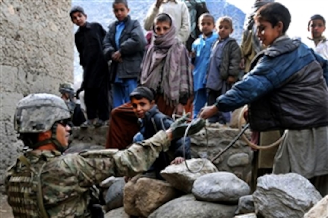 U.S. Army Staff Sgt. Dennis L. Famisan borrows a toy from a young boy in the village of Kandagal in the Monagai district of eastern Afghanistan’s Kunar province, Feb. 20, 2010. The unit was there to drop off replacement equipment for a broken well pump. International forces often visit Afghan villagers to check on their health, safety and welfare. Famisan is a section sergeant assigned to Company D, 2nd Battalion, 12th Infantry Regiment.