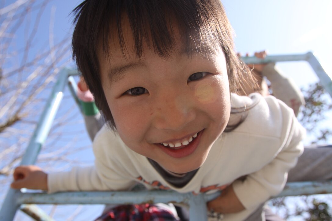 A Japanese preschooler peers into the camera during reccess with some local Marines and sailors at Iwakuni Hoikuen Kuroiso Feb. 24. During reccess, service members gathered the children into a large circle for a game of duck, duck,  goose.