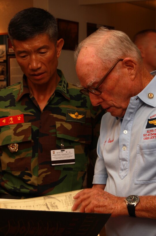 (From right to left) Retired Navy Capt. Charles "Davy" Crockett, a pilot during the Korean War, shows Republic of Korea Lt. Capt. Kinam Lee, ROK Marine Corps Liason to U.S. Marine Corps Forces, Pacific, aerial maps and discusses the Korean War Feb. 25 at the Sunset Lanai, Camp H.M. Smith, Hawaii. Retired veterans with The Chosen Few's Aloha Chapter gave a Korean War presentation to service members with MarForPac.