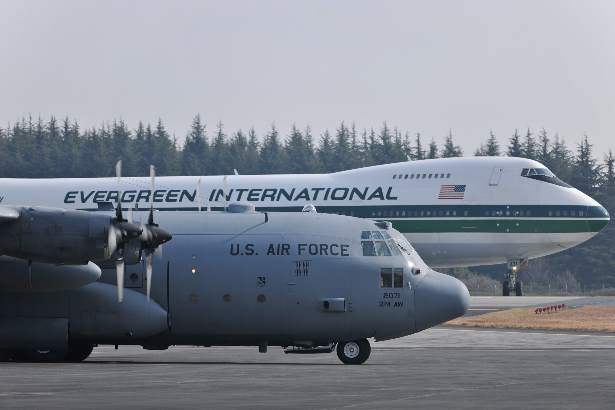 YOKOTA AIR BASE, Japan -- The C-130 Hercules-J aircraft waits for a Boeing 747-300 to taxi here, Feb. 23. (U.S. Air Force photo/Osakabe Yasuo)