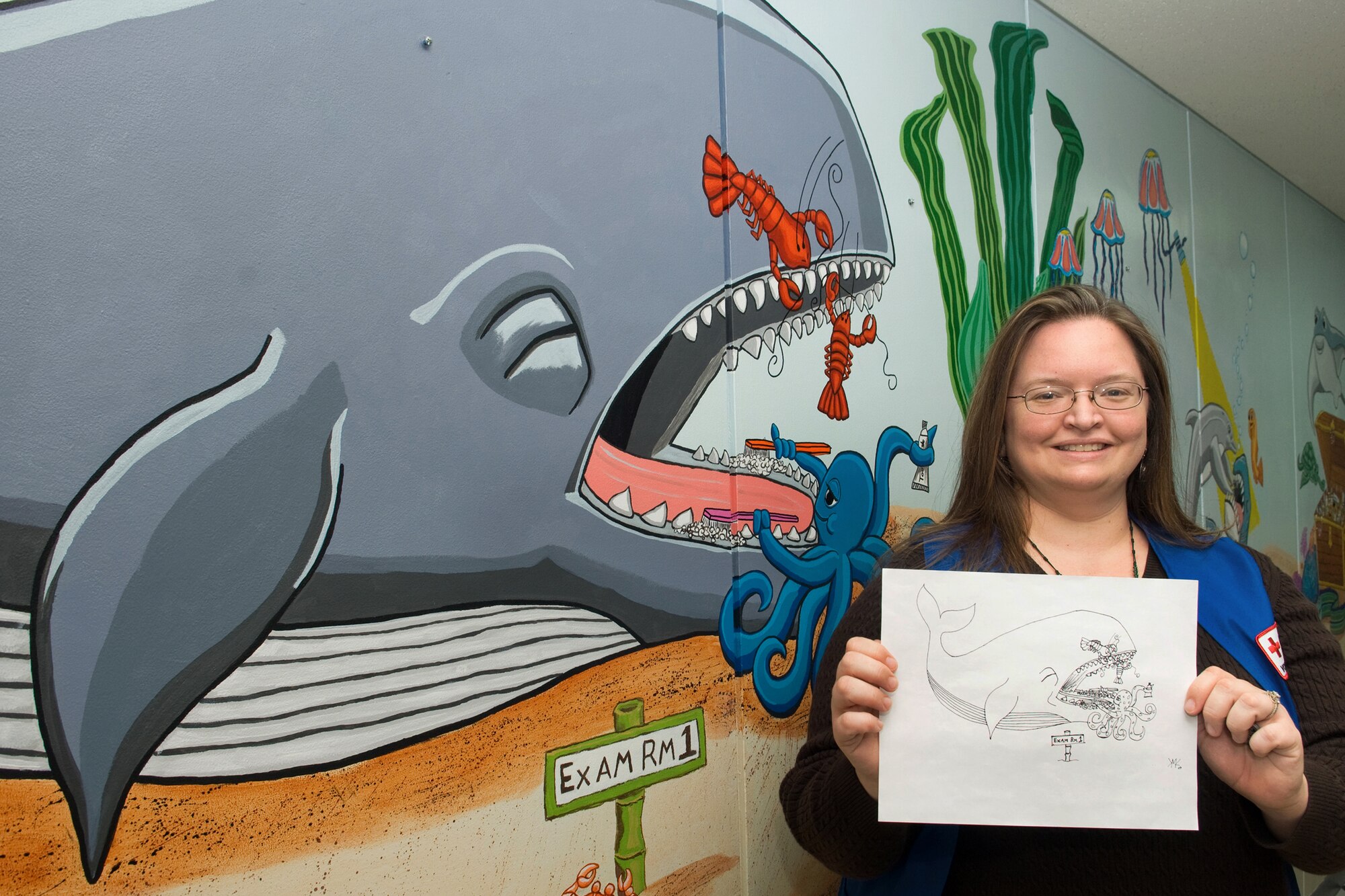 YOKOTA AIR BASE, Japan -- Mrs. Kelley Monkevich, American Red Cross volunteer, shows off her original drawing used to create part of a mural on a wall at the 374th Dental clinic children's waiting room, here, Feb. 26.  Mrs. Monkevich worked more than 100 hours painting and refurnishing the children’s waiting room at the dental clinic. (U.S. Air Force photo/Osakabe Yasuo)