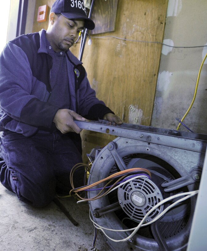 Brandon Keys, 316th Civil Engineer Squadron maintenance mechanic assigned to the Heating and Air Condition Shop, inspects a problematic furnace blower motor in the mechanical room behind the Air Force Reserve Air National Guard Recruiting Center, Bldg. 1840. The furnace was scheduled for replacement Thursday. (U.S. Air Force photo/ Bobby Jones)