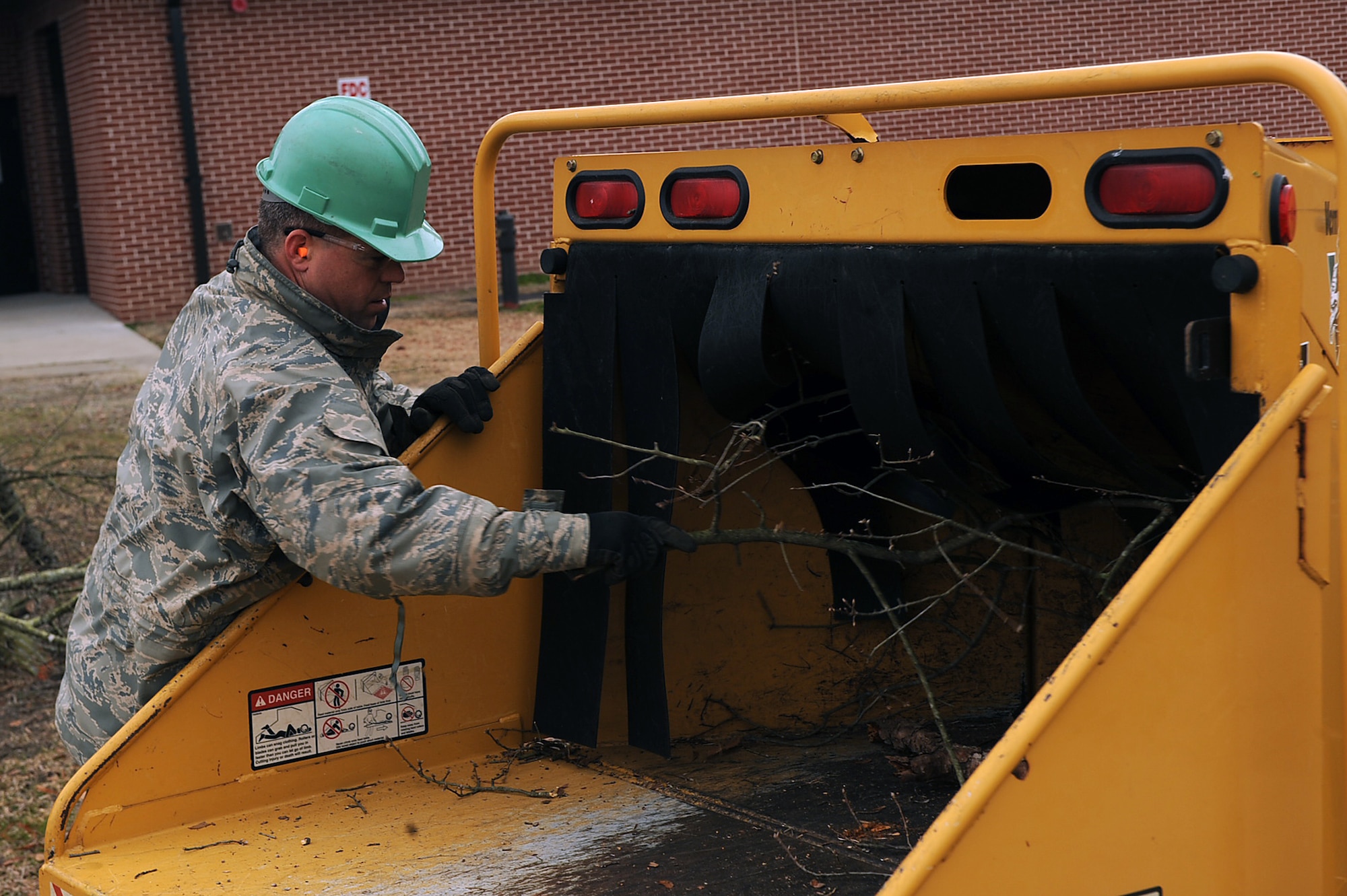 Tech Sgt. Robert Echols, 567th RED HORSE Squadron heavy equipment operator, pushes tree limbs into a wood chipper on Seymour Johnson Air Force Base, N.C., Feb. 24, 2010. After the Airmen prune the branches they place them in a wood chipper, remains are taken to a waste industries site off-base for use as mulch and compost. Echols hails from Ludlow, Mass. (U.S. Air Force photo/Senior Airman Ciara Wymbs) 