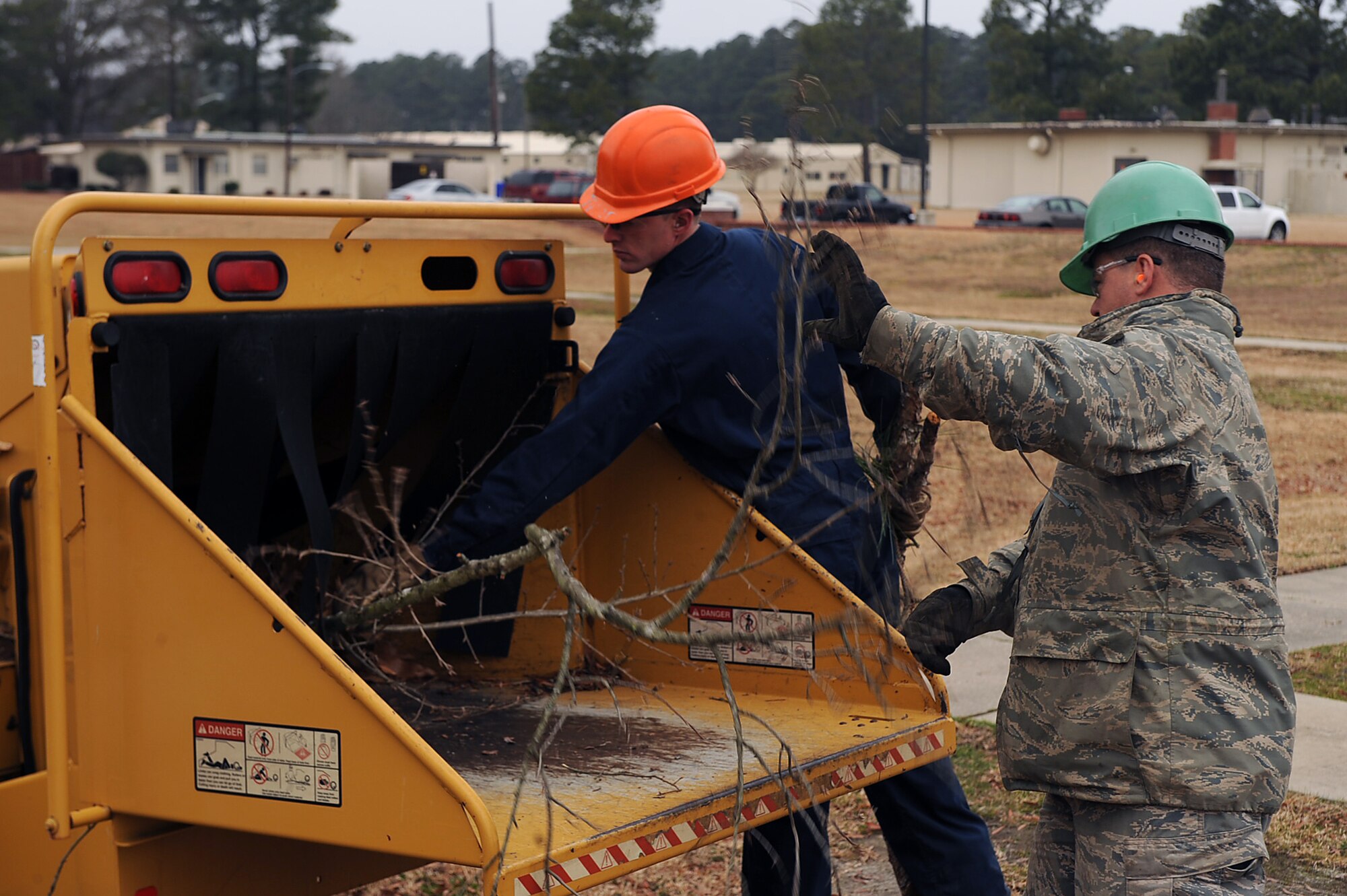 Tech Sgt. Robert Echols (right), 567th RED HORSE Squadron heavy equipment operator, and Staff Sgt. Daniel Steenstra, 201st RED HORSE Squadron Detachment 1 heavy equipment operator, push tree limbs into a wood chipper on Seymour Johnson Air Force, Base, N.C., Feb. 24, 2010. After bad weather damages trees or when tree branches begin to grow to close to buildings, work orders are put in for them to be cut down. Echols hails from Ludlow, Mass. and Steenstra is from Shippensburg, Pa. (U.S. Air Force photo/Senior Airman Ciara Wymbs) 