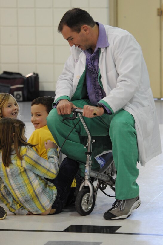 Capt. Bradley Harrelson, 28th Medical Operations Squadron dentist, also known as Dr. Juggles, rides a tricycle to entertain children at Francis Case School, Box Elder, S.D., Feb. 17. Dr. Juggles provides entertainment for children in hopes they will learn the importance of dental health and oral hygiene in a fun way. (U.S. Air Force photo/Airman 1st Class Corey Hook)