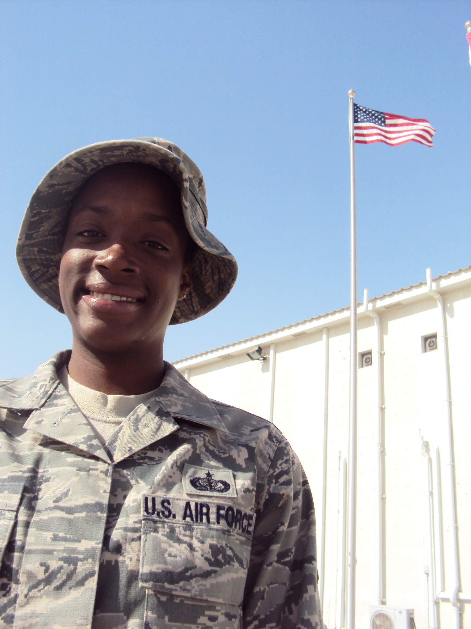 Staff Sgt. Sparkle Reid, a services journeyman, is deployed as the non-appropriated funds custodian for the 380th Expeditionary Force Support Squadron at a non-disclosed base in Southwest Asia.  Here she is pictured by the American flag by the 380th Air Expeditionary Wing headquarters on Feb. 25, 2010. Sergeant Reed lost her uncle, Louie A. Williams, when the World Trade Center towers came down on Sept. 11, 2001. He worked on the 66th floor of the North Tower for the New York Port Authority as a paralegal. On Feb. 27, 2009, Sergeant Reid lost her father, Charles T. Reid, after complications from surgery. She credits both her uncle and her father as her inspiration for serving. Sergeant Reid is deployed from from the 48th Force Support Squadron at RAF Lakenheath, England, and her hometown is Queens, N.Y. (U.S. Air Force Photo/Master Sgt. Scott T. Sturkol/Released)