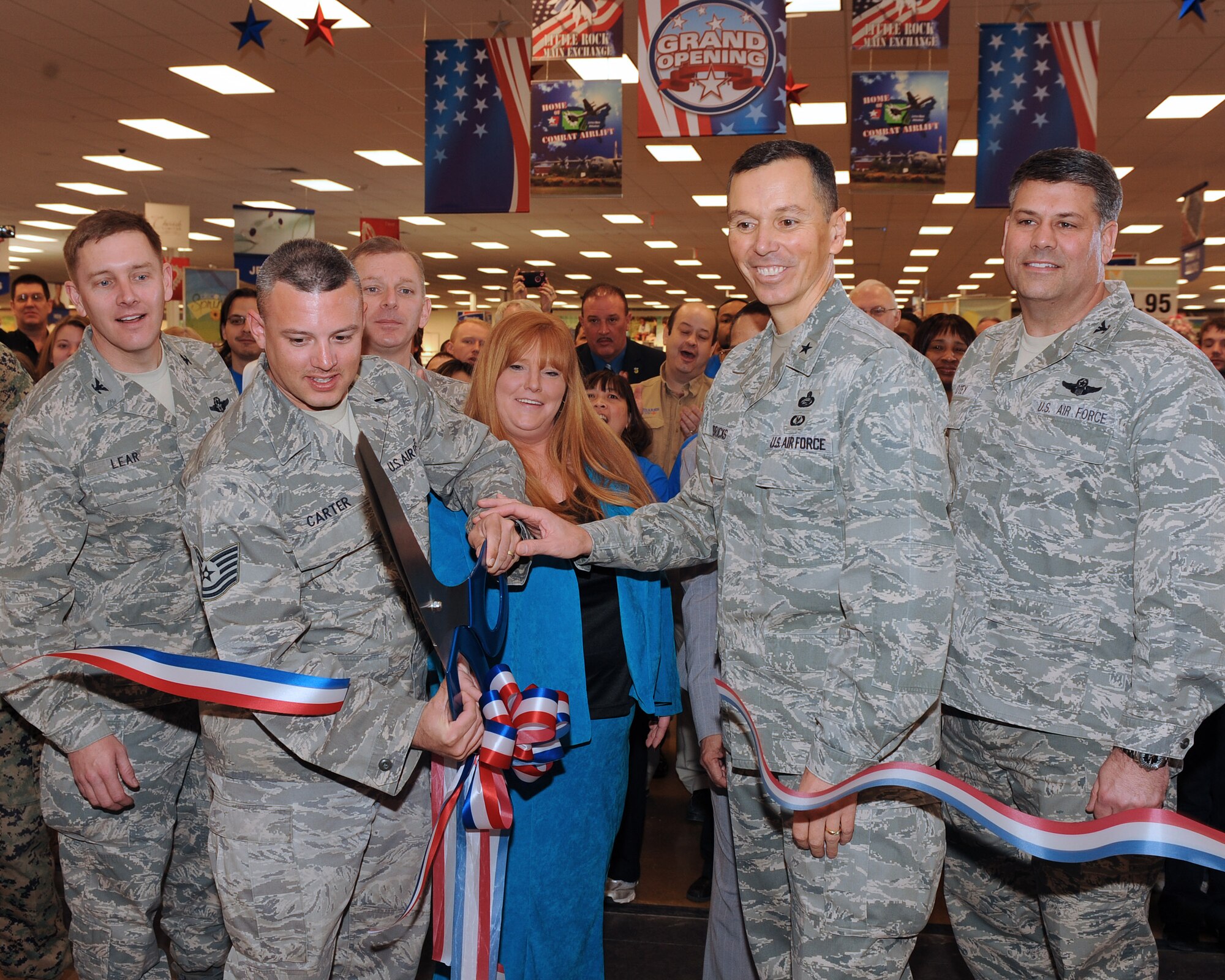 (From left) Col. Kirk Lear, 314th Airlift Wing vice commander; Tech. Sgt. Dwight Carter, 19th Aircraft Maintenance Squadron crew chief; with his wife, Donna, 19th Aircraft Maintenance Squadron key spouses advisor; Brig. Gen. Francis Hendricks, Army and Air Force Exchange Services vice commander; Col. Greg Otey, 19th Airlift Wing commander; cut the ribbon Feb. 25 at the grand opening of the new base exchange, while Chief Master Sgt. Jeffry Helm, AAFES senior enlisted advisor; and base exchange staff look on.  Sergeant Carter and Mrs. Carter were representing the Year of the Air Force Family and given the honor of cutting the ribbon, officially opening the building to customers. (U.S. Air Force photo by Staff Sgt. Chad Chisholm)