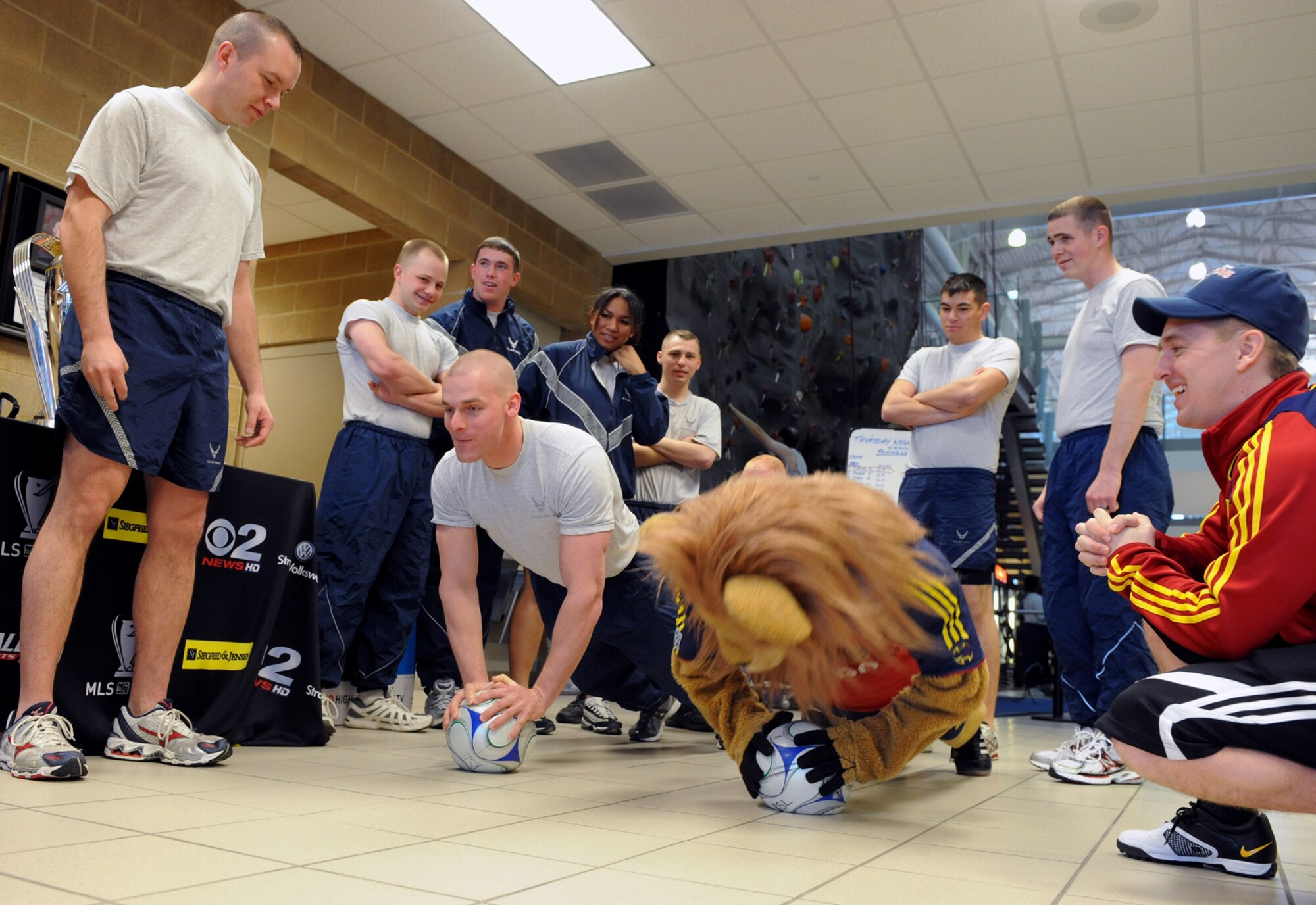 Senior Airman Michael Sprouse, of the 729th Air Control Squadron, competes in a push-up contest with ReAL Salt Lake mascot, Leonardo the Lion. Behind them are members of the Hill Air Force Base Honor Guard. Leonardo accompanied the Major League Soccer Championship Cup trophy which is traveling all around the state of Utah with RSL representatives. The Feb. 23 visit to Hill Air Force Base began with an early morning stop at the Warrior Health and Fitness Center and was to include a drop by visit to the Youth Center and other sites at the base. The Utah RSL tour will include a series of photos with fans and community members along the way and will be posted on the ReAL Flickr site and Behind the Lines ReAL Salt Lake's official blog. 