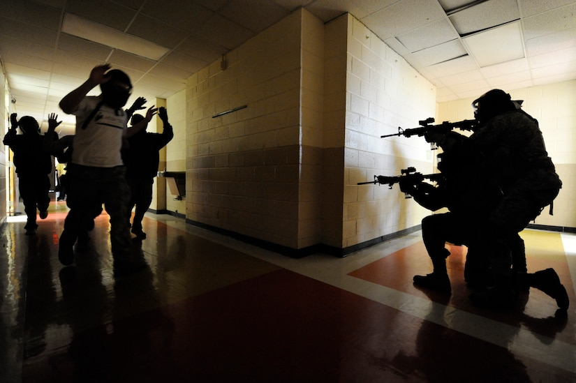 Mock hostages run by as security forces members prepare to shoot an aggressor during the Active Shooter Training Course at Mt. Pleasant, S.C., Feb. 23, 2010. The AST course prepares first responders on how to react to a hostile situation. (U.S. Air Force photo by James M. Bowman/released)

