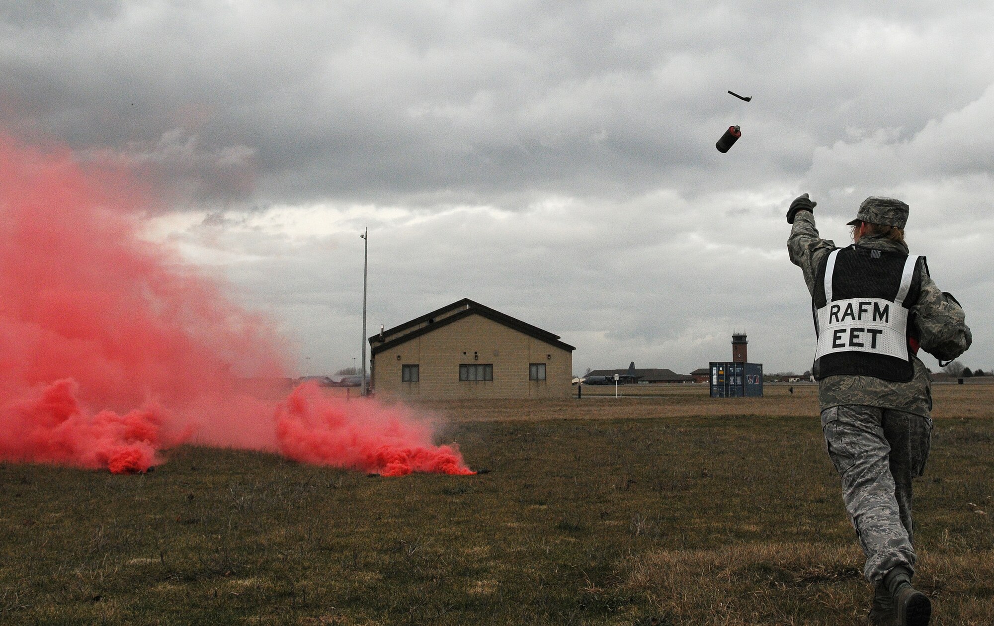 RAF MILDENHALL, England -- Master Sgt. Ani Stubbs, Exercise Evaluation Team member, throws M18 red smoke hand grenades during a simulated ground attack at Base X here Feb. 25. Evaluators conducted the operational readiness exercise to test 100th Air Refueling Wing Airmen on their response to wartime scenarios. (U.S. Air Force photo/Senior Airman Thomas Trower) 