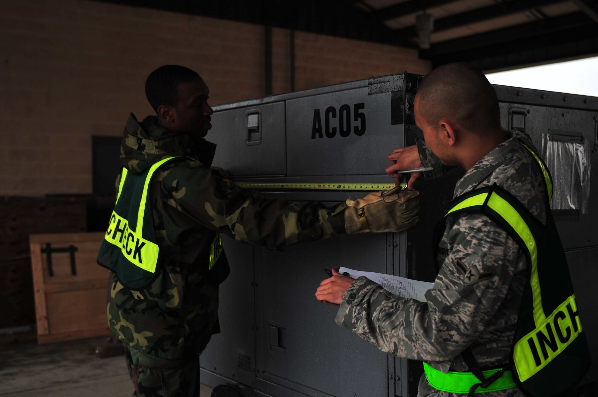 Senior Airman James Moore, 4th Force Support Squadron food service journeyman, and Airman Argel Misenas, 4th Logistics Readiness Squadron receiving apprentice, measure cargo during a Phase I exercise on Seymour Johnson Air Force Base, N.C., Feb. 22, 2010.  The Airmen weigh and measure the cargo's length, height, and width to ensure it will fit on the transport aircraft. Moore hails from Little Rock, Ark. and Misenas is from San Jose, Calif. (U.S. Air Force photo/Senior Airman Rae Perry)