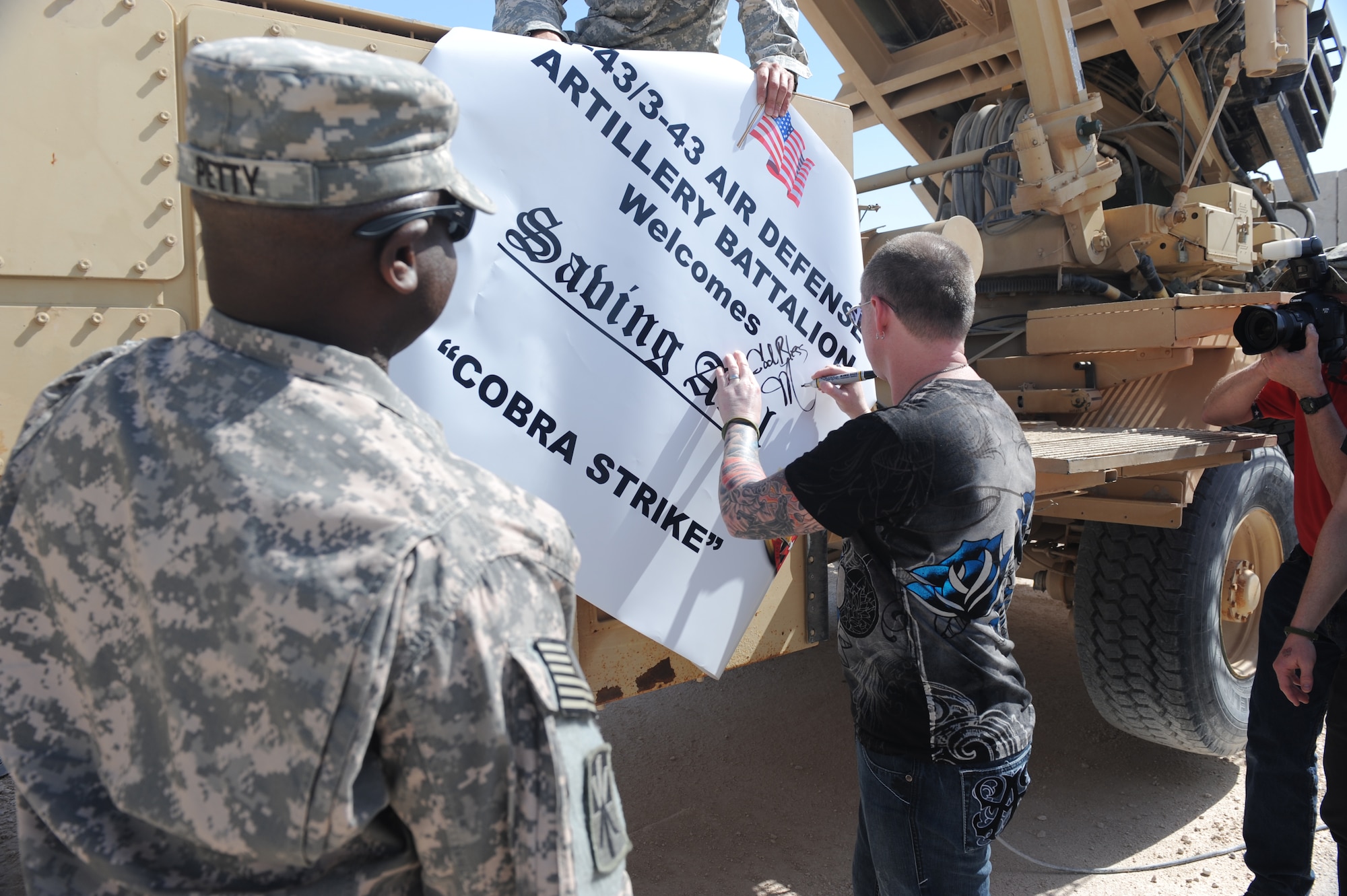 Lead guitarist Jason Null of national recording artists Saving Abel signs a banner for Army Patriot Missile Soldiers prior to a live concert performance for servicemembers at a non-disclosed Southwest Asia location, Feb 22, 2010. (U.S. Air Force photo by Tech. Sgt. Michelle Larche)[RELEASED]