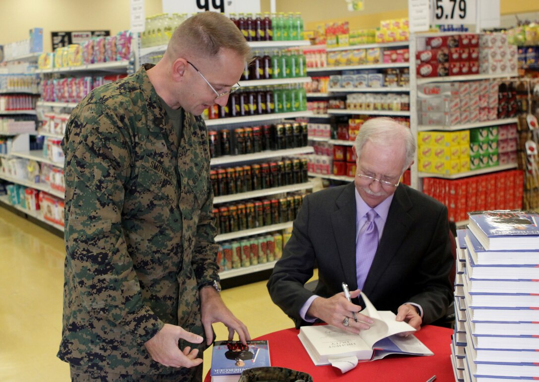 Captain Chesley “Sully” Sullenberger, commercial airline pilot, who piloted a distressed passenger plane to safety onto the Hudson River in New York City, signs a copy of his new book for Gunnery Sgt. Sean Smothers, imagery analysis specialist, 1st Intelligence Battalion, 1st Marine Expeditionary Force, at Camp Pendleton’s Country Store, Feb. 25. Sullenberger talked to Marines, sailors and family members and signed copies of his new book, “Highest Duty: My Search for What Really Matters,” that recounts his life as a pilot and describes the onslaught of sudden celebrity after making an emergency landing where all the passengers survived Jan. 15, 2009.