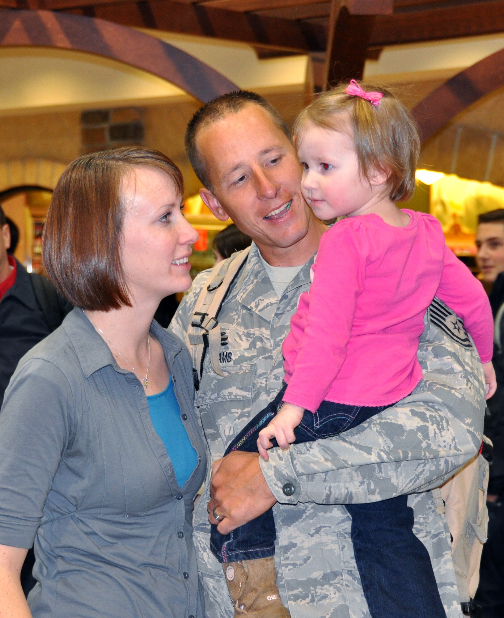 Tech. Sgt. Justin Adams and his wife, Aubrey, try to persuade their daughter, Claire, age 2, to smile for the cameras. (U.S. Air Force photo/Bryan Magaña)