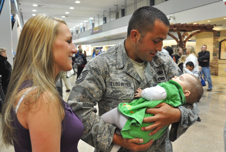 Tech. Sgt. Cody De Los Reyes, 67th Aerial Port Squadron, cradles his 8-month-old daughter as wife, Keri, looks on. Sergeant De Los Reyes returned home Feb. 26 after a month-long deployment to Haiti, where he and 14 other Air Force Reservists from Hill Air Force Base's 419th Fighter Wing helped restore airfield operations at the Toussaint Louverture International Airport in Port-au-Prince. (U.S. Air Force photo/Bryan Magaña)