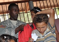 Specialist Leroy Stokes, Joint Task Force-Bravo member at Soto Cano Air Base, Honduras puts a pack on one of more than 1,000 children who received backpacks in rural areas of Honduras in conjunction with Give a Kid a Backpack Feb. 24. Give a Kid a Backpack is a nonprofit organization that works towards enriching the lives of impoverished children around the world with backpacks filled with school supplies through the partnership with other nonprofit organizations. (U.S. Air Force Photo/Staff Sgt. Bryan Franks)