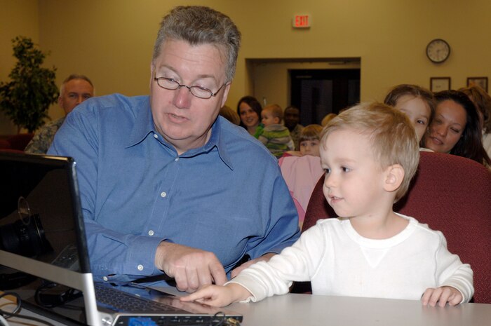 Dave Mason helps Connor Trejo start the wing mission video during the Little Heroes ceremony held at the Education and Training Center Feb. 25 at Joint Base Charleston. Little Heroes is a ceremony to recognize children for the sacrifices they made during a parent’s recent deployment. Each child is presented with a medallion with a C-17 imprinted on the face and a certificate signed by the parent’s respective wing commander. Mr. Mason is the husband of Flora Mason who is with the Airman and Family Readiness Center, and Connor is the stepson of Staff Sgt. Chris Koch who is with the 437th Operations Support Squadron. (U.S. Air Force photo/Staff Sgt. Marie Brown/Released)