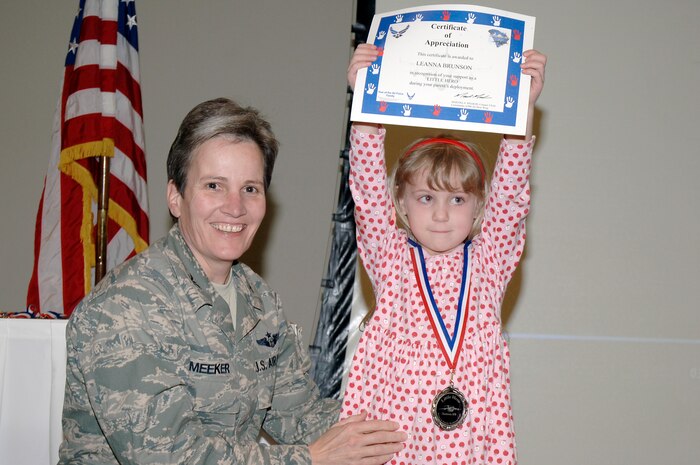 Col. Martha Meeker presents a certificate to Leanna Brunson as she proudly displays it above her head during the Little Heroes ceremony held at the Education and Training Center Feb. 25 at Joint Base Charleston. Little Heroes is a ceremony to recognize children for the sacrifices they made during a parent’s recent deployment. Each child is presented with a medallion with a C-17 imprinted on the face and a certificate signed by the parent’s respective wing commander. Colonel Meeker is the 628th Air Base Wing commander and Leanna is the daughter of Chaplain (Capt.) Gregory and Sherri Brunson with the 628th ABW. (U.S. Air Force photo/Staff Sgt. Marie Brown/Released)