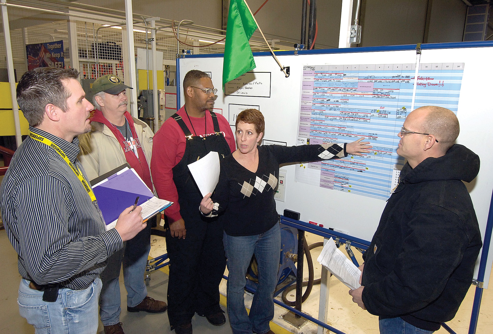 A simple change, reflective of Tinker’s ongoing Lean thinking, was a major improvement in helping Bldg. 3102’s Inspection Dock work and a morale boost.  New boards give up-to-date knowledge to mechanics and supervisors and alert to hold ups or successes where every hour delay can affect a process chain with more than 100 hand-offs.  Craig Smith, I-Dock chief; sheet metal mechanic John Dixon; aircraft mechanic Rodney Radford; aircraft logistics specialist Lori Wilson; and aircraft mechanic Robert McCoy, from left, meet twice daily to update information.  (Air Force photo by Margo Wright)
