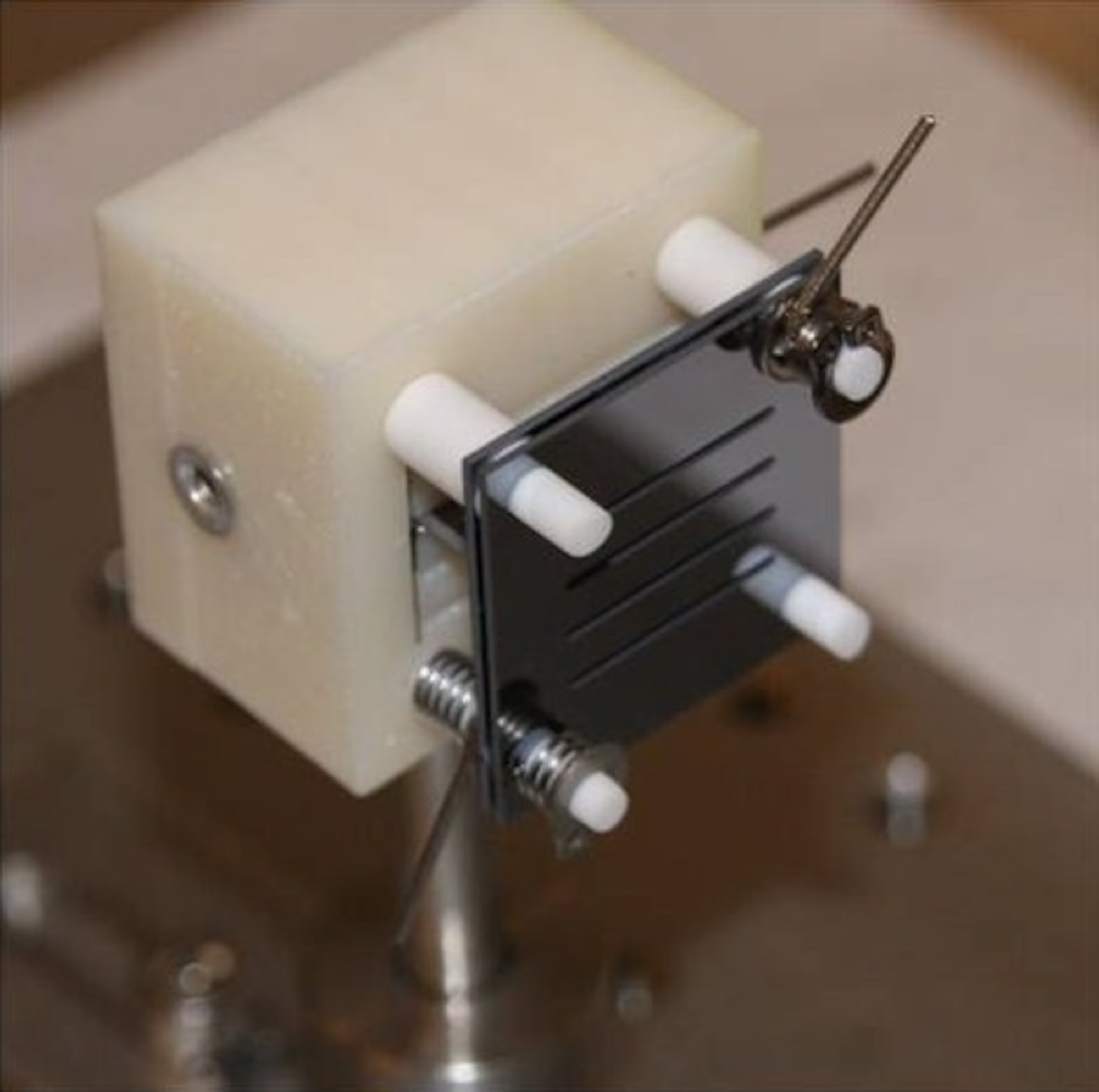 A prototype of a miniature electrospray thruster with four rows of ion emitters is shown here. The thruster is contained within two black plates each measuring about one square inch. (Credit: Dr. Paulo Lozano, MIT)