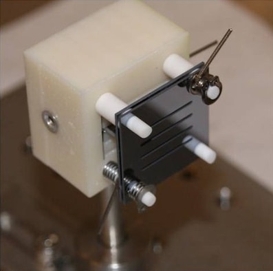 Pictured is a miniature electrospray thruster prototype developed by Massachusetts Institute of Technology (MIT) researchers via AFRL funding.  The mini-thruster, complete with its four rows of ion emitters, is contained within two black plates, each measuring about 1 sq in. (Credit:  Dr. Paulo Lozano, MIT)