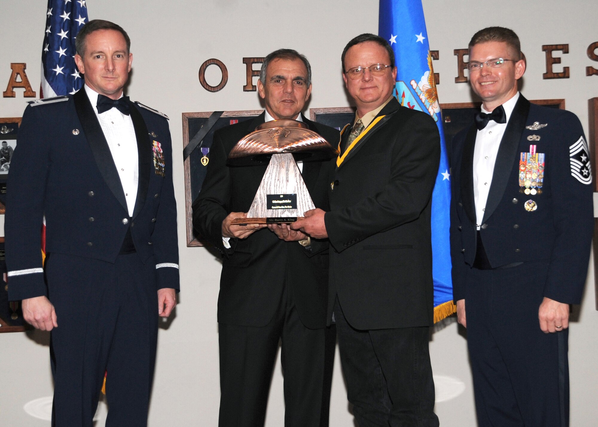 Barry King, 27th Special Operations Mission Support Group, receives the Category III Civilian of the Year award from (left) Col. Stephen Clark, 27th Special Operations Wing commander, Retired Air Force Maj. Gen. Richard Comer, and (right) Chief Master Sgt. William Turner, wing command chief. The wing's top Airmen and civilians were recognized at the annual awards dinner at The Landing Zone Feb. 20 at Cannon Air Force Base, N.M.(U.S. Air Force photo by Airman 1st Class Maynelinne De La Cruz) 