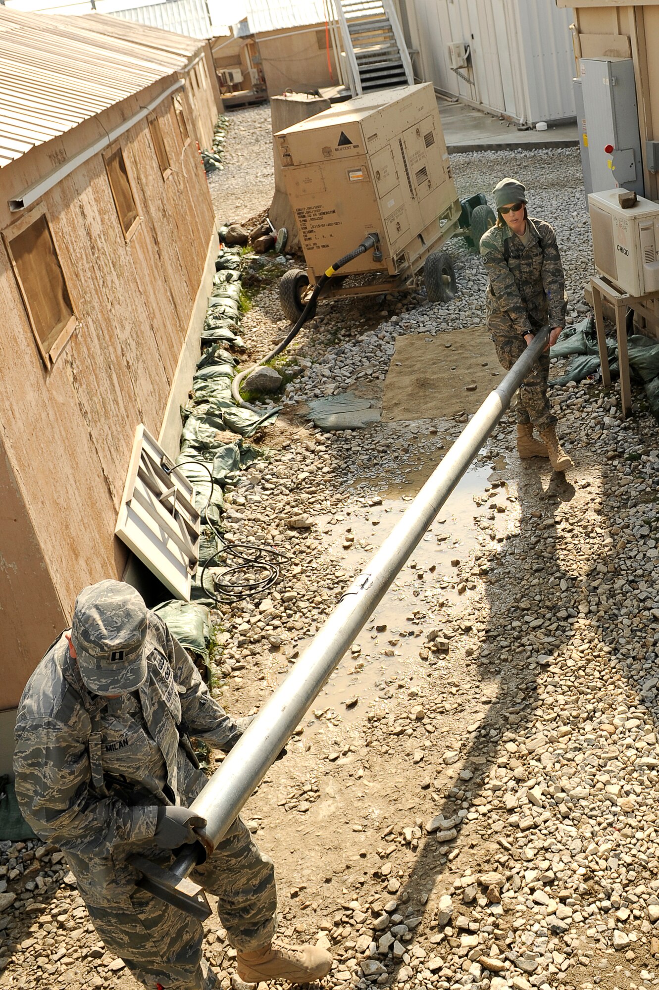 U.S. Air Force Capt. Jose Milan (front), and Staff Sgt. Emily Johanneck, 455th Air Expeditionary Wing, Sexual Assault Response Coordinator office, carry a light pole for a solar powered light being installed at Bagram Airfield, Afghanistan, Feb. 23, 2010. Captain Milan is deployed from Hill Air Force Base, Utah, and is from Navasota, Texas. Sergeant Johanneck is deployed from Tinker AFB, Okla., and is from Waseca, Minn. (U.S. Air Force photo by/ Tech. Sgt. Jeromy K. Cross/released)