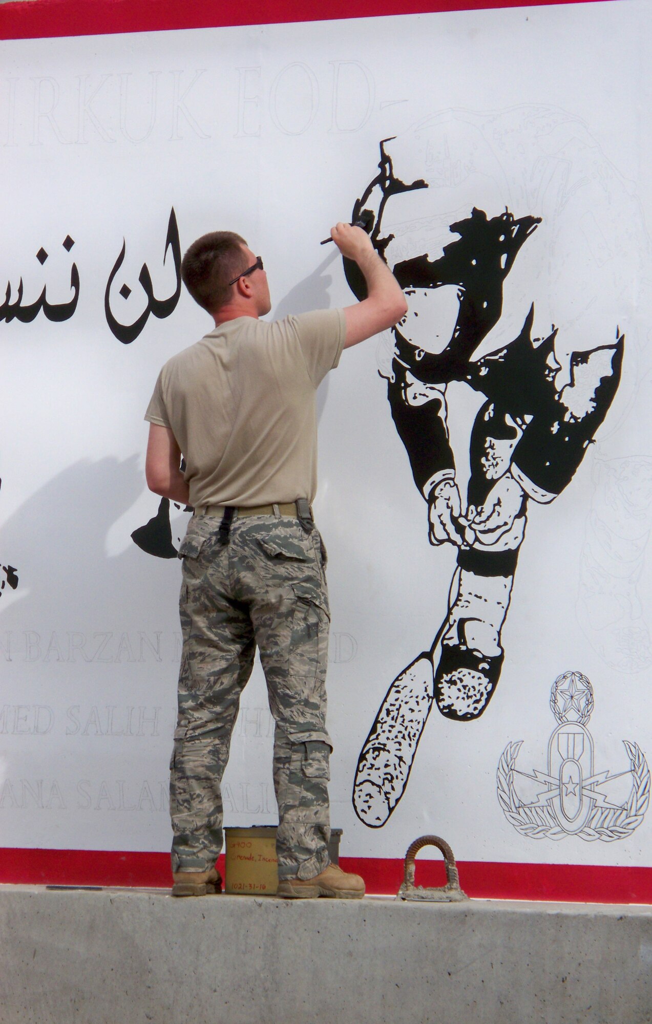 Tech. Sgt. Eric Eberhard, 506th Civil Engineer Squadron Explosive Ordnance Disposal team leader deployed from Hill AFB, Utah, paints a mural on one of the concrete walls at the EOD compound on Kirkuk Regional Air Base to honor three fallen Iraqi Police counter explosive team members for an unveiling ceremony held Feb. 23, 2010.  (U.S. Air Force courtesy photo/Released)