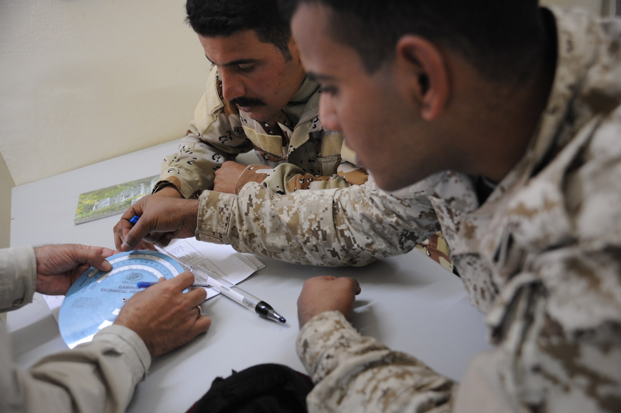 Two students from the petroleum oil & lubrication class view a demonstration on how to use a gravity and density calculator during class at Camp Taji, Iraq, Feb. 13, 2010. This POL class is advised by U.S. Air Force personnel who teach the Iraqi military how to be self sufficient in protecting their equipment and personnel while checking fuel for contaminants that can be potentially hazardous. (U.S. Air Force photo/Master Sgt. Trish Bunting/Released)