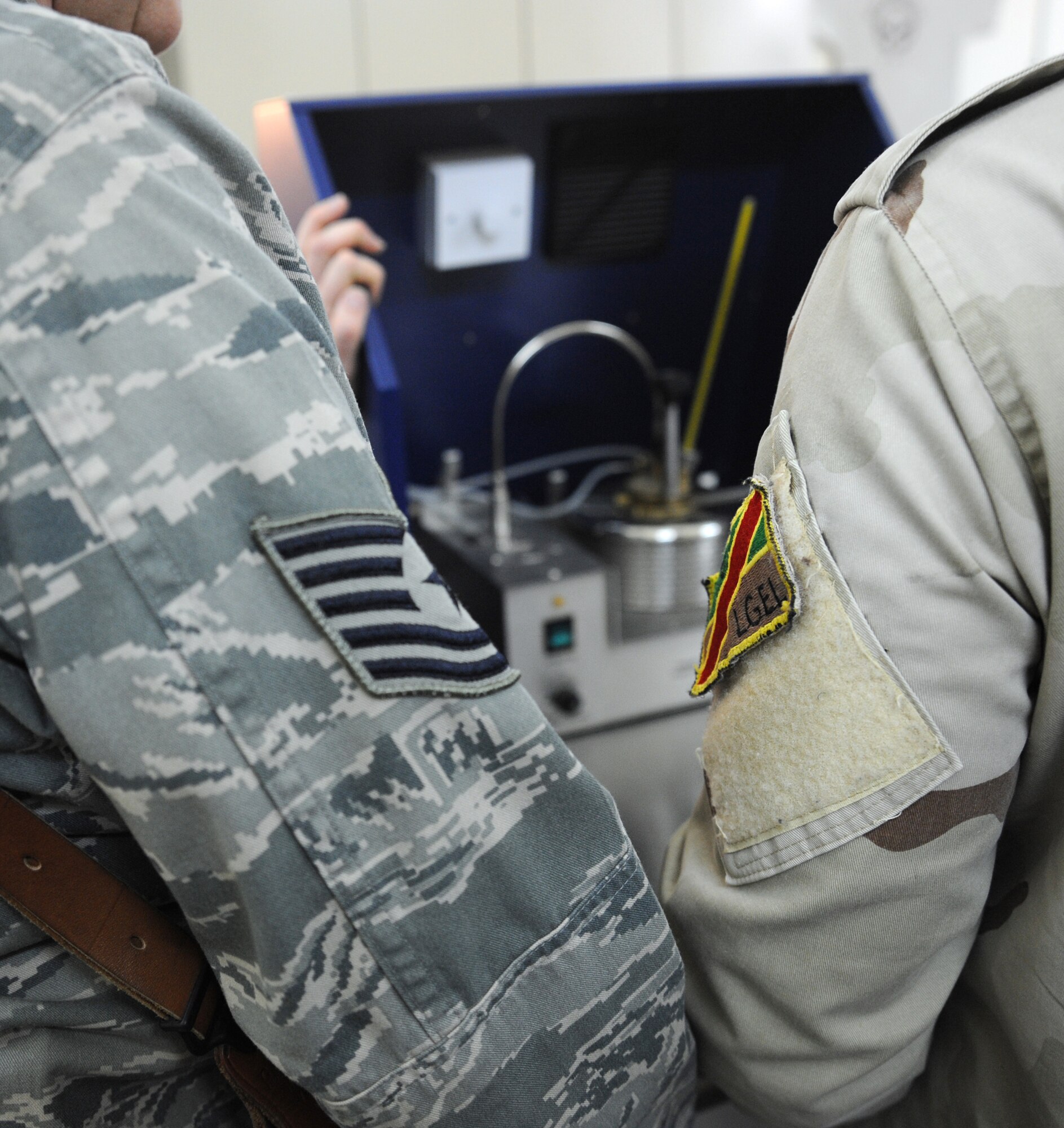 U.S. Air Force Tech. Sgt. Kathleen Franklin, 821st Expeditionary Training Squadron petroleum oil & lubrication class advisor, stands next to an Iraqi student during a demonstration on how to use a Flash Point Tester during class at Camp Taji, Iraq, Feb. 13, 2010. This POL class is advised by U.S. Air Force personnel who teach the Iraqi military how to be self sufficient in protecting their equipment and personnel while checking fuel for contaminants that can be potentially hazardous. (U.S. Air Force photo/Master Sgt. Trish Bunting/Released)