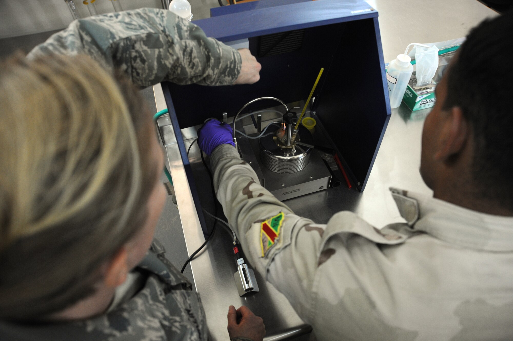 U.S. Air Force Tech. Sgt. Kathleen Franklin, 821st Expeditionary Training Squadron petroleum oil & lubrication class advisor, displays to an Iraqi student how to use a Flash Point Tester during class at Camp Taji, Iraq, Feb. 13, 2010. This POL class is advised by U.S. Air Force personnel who teach the Iraqi military how to be self sufficient in protecting their equipment and personnel while checking fuel for contaminants that can be potentially hazardous. (U.S. Air Force photo/Master Sgt. Trish Bunting/Released)