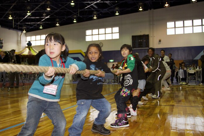 Ayaka Yamakawa (left), Cameron Olivas (center) and Reina Yamamoto (right), team up against an effort to pull the opposing team across the line in a game of tug-of-war during the US-Japan Friendship Exchange at Marine Corps Air Station Iwakuni, Japan Feb. 27.  The friendship exchange brought students from M.C. Perry Elementary School and Kawashimo Elementary School together with a series of avtivities including kite making, tug-of-war, basketball, dodgeball, and much more.  With an opportunity to interact and play, students and their parents were able to share cultural experiences and form a common bond.