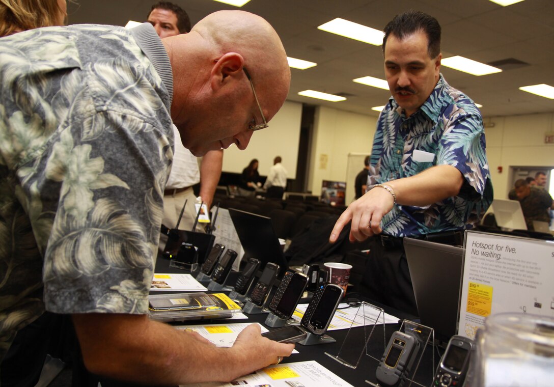 (From left to right) Michael Silven, U.S. Marine Corps Forces, Pacific's, information management officer, browses a selection of cellular phones while Adrian DiTucci, a Sprint account manger, explains their software features March 1 at U.S. Marine Corps Forces, Pacific, Camp H. M. Smith, Hawaii during the 2010 Technology and Industry Day. Officials with U.S. Pacific Command's Joint Communications Section host the annual event to introduce service members to new technologies that may enhance military operations, whether deployed or in garrison.
