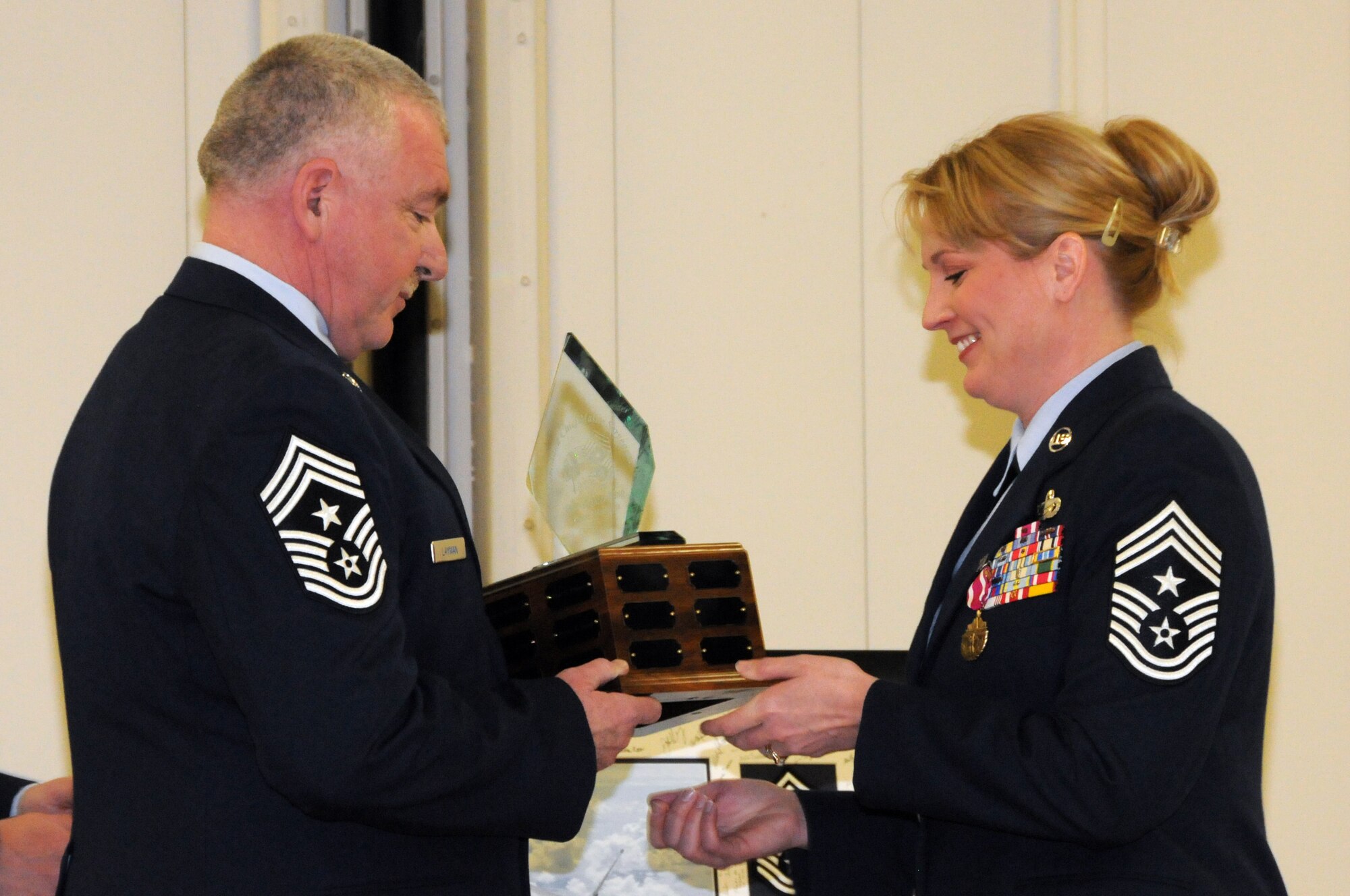Newly appointed Command Chief Master Sgt. Michael Layman (left) accepts the 148th Fighter Wing's Command Chief plaque from retiring Command Chief Master Sgt. Jodi Stauber during a transfer of authority ceremony held at the wing in Duluth, Minn. Feb. 28th, 2010.  The plaque is symbolic of the authority the Command Chief holds while acting in this prestigious role. (U.S. Air Force photo by Staff Sgt. Donald Acton)