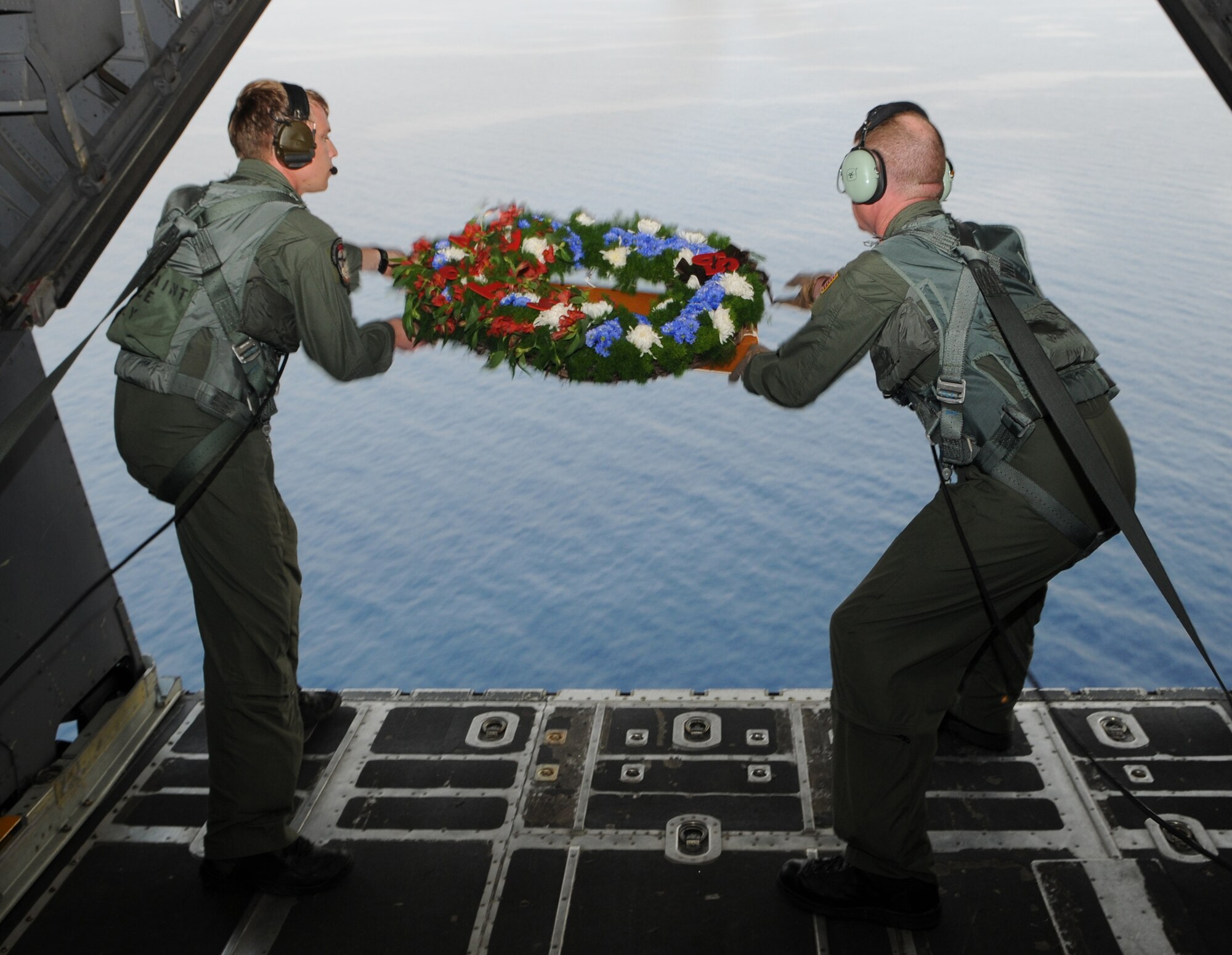 NEAR CAPONES ISLAND, Philippines -- Staff Sgt. Jim Kosnosky (left) and Tech. Sgt. Aaron Kay, 1st Special Operations Squadron loadmasters, release a memorial wreath out the back of a MC-130H Combat Talon II Feb. 26 to honor fallen brethren that were lost 28 years ago when a 1st SOS MC-130E, call sign STRAY 59, crashed during an exercise killing eight crew members and 15 passengers. The crew of GOOSE 99 flew from Kadena Air Base to reach the exact coordinates of the crash site to release the ceremonial wreath. The memorial flight has been flown every year since the tragic accident in 1981. (U.S. Air Force photo by Tech. Sgt. Aaron Cram)