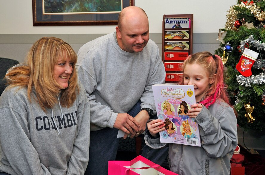 FAIRCHILD AIR FORCE BASE, Wash. – Tech. Sgt. Dewey Brown and wife, Sharon, watch as their daughter, Cami, 7, opens Christmas gifts provided by the Fairchild Airman and Family Readiness Center here Dec 22. The Brown family’s gifts were taken, along with all of their belongings, from their U-Haul truck Dec. 20.  (U.S. Air Force Photo / Senior Airman Darlene West)
