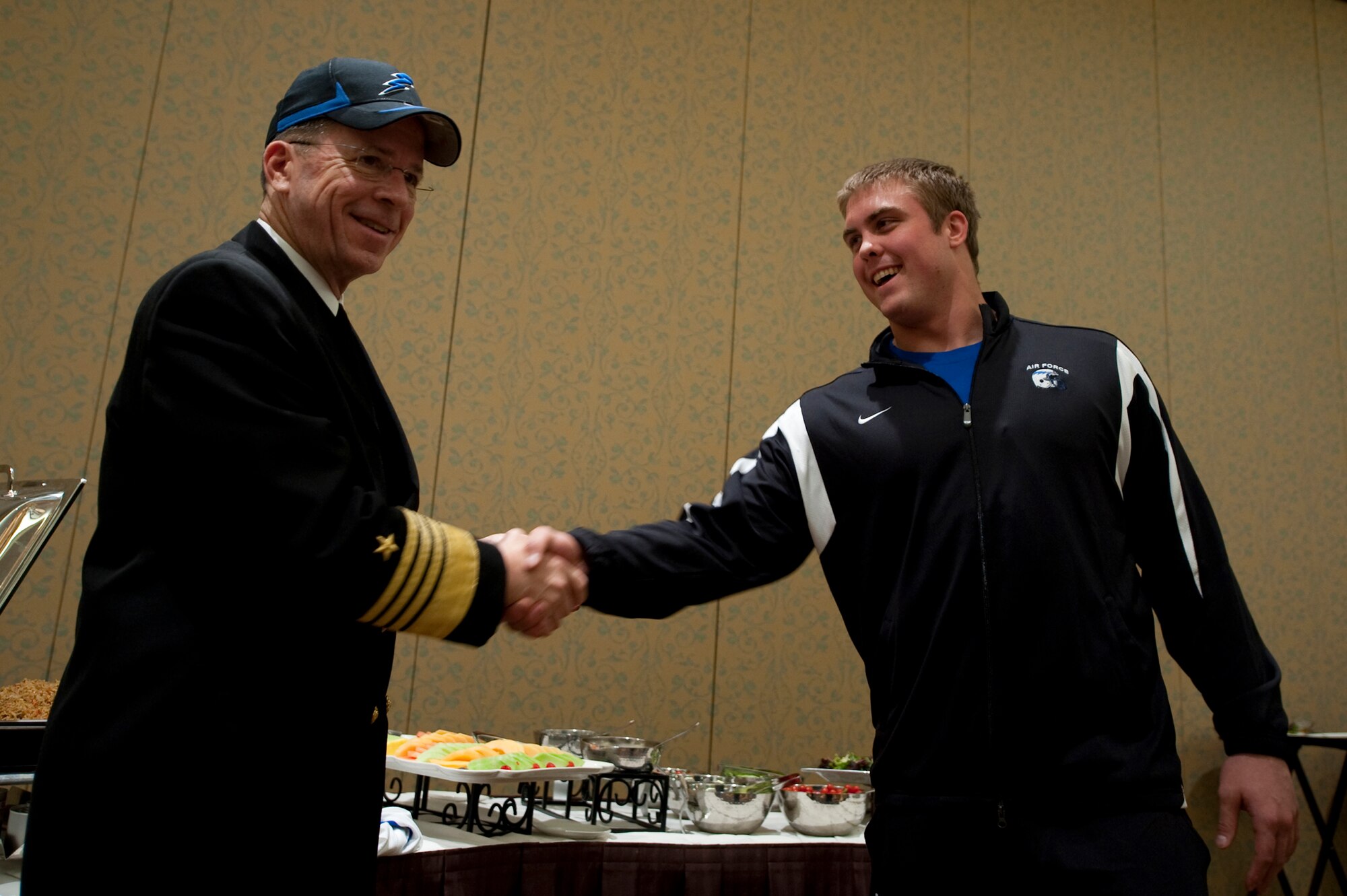 Adm. Mike Mullen, chairman of the Joint Chiefs of Staff, receives an Air Force Academy Falcons ball cap from senior nose guard Ben Garland Dec. 30, 2009, after meeting with the team during a visit the day before the Armed Forces Bowl in Fort Worth, Texas.  The Falcons won the bowl game, defeating the University of Houston Cougars 47-20.  (Defense Department photo/Petty Officer 1st Class Chad J. McNeeley)